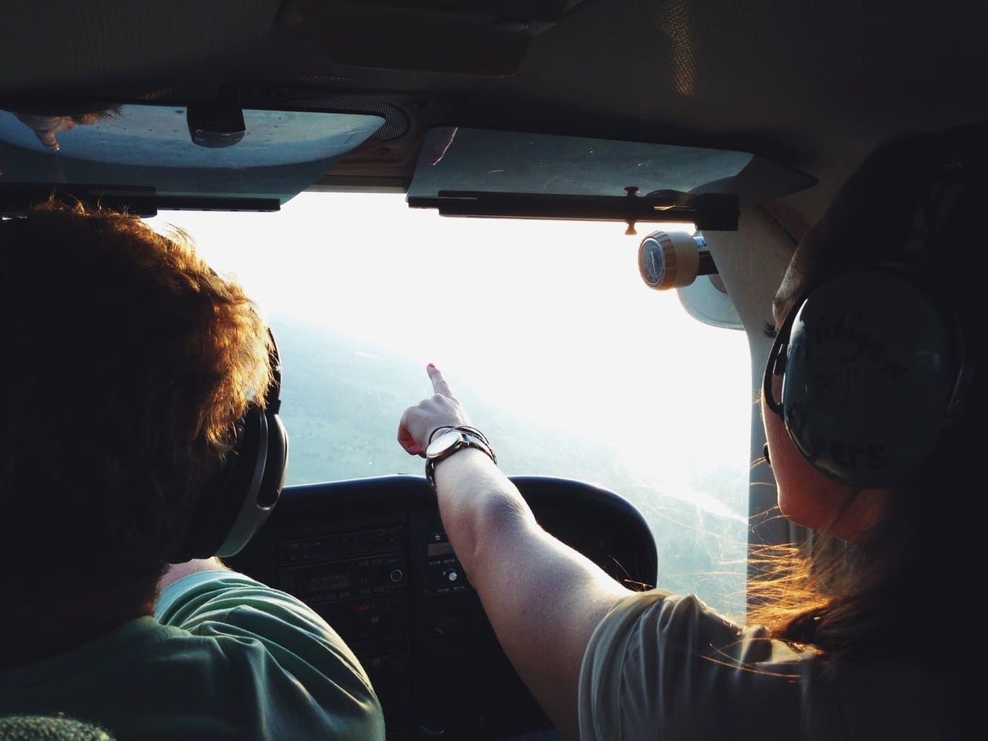 Two people in a light aircraft cockpit looking out towards the horizon