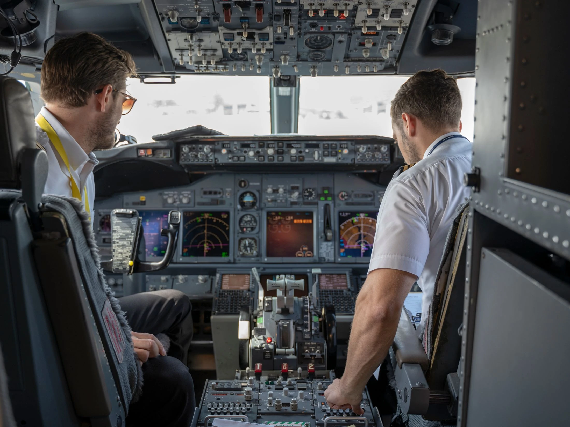Two pilots working together at the controls of a commercial aircraft